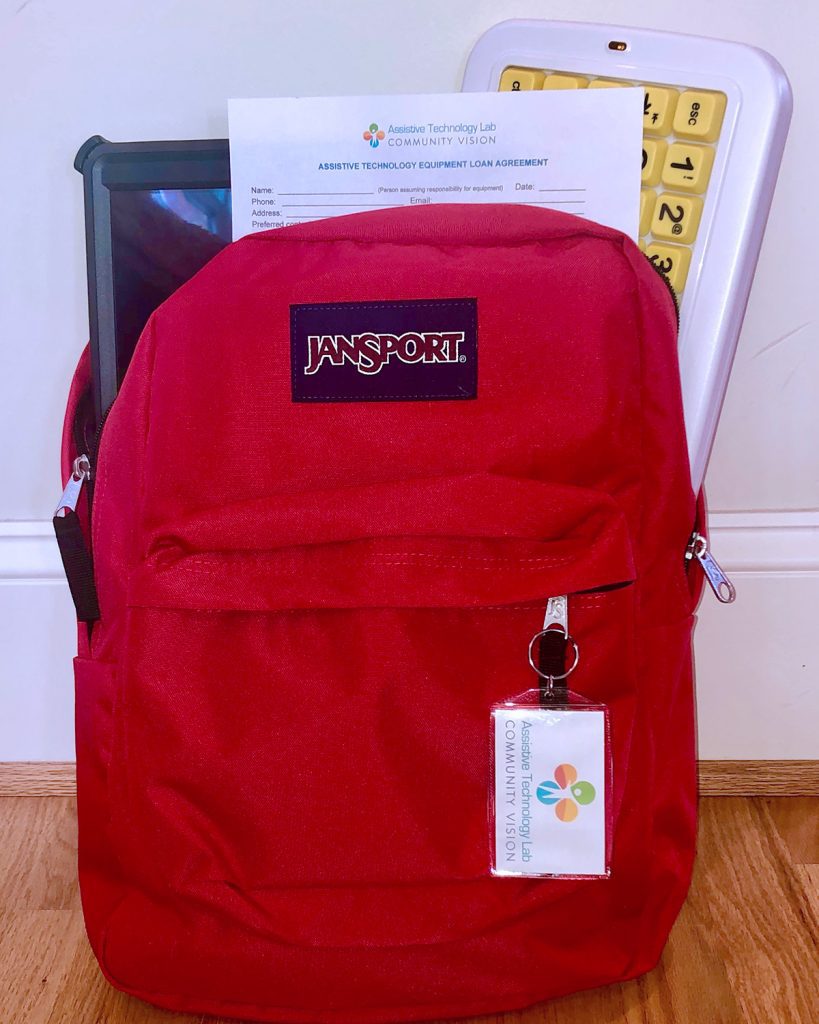A red backpack holds a communication device, adaptive keyboard, and a loan closet check-out form