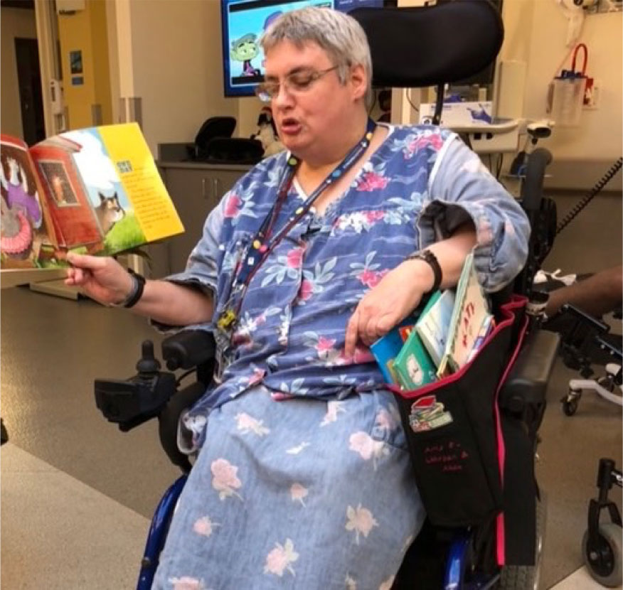 Woman, who uses a wheelchair, holding up a picture book